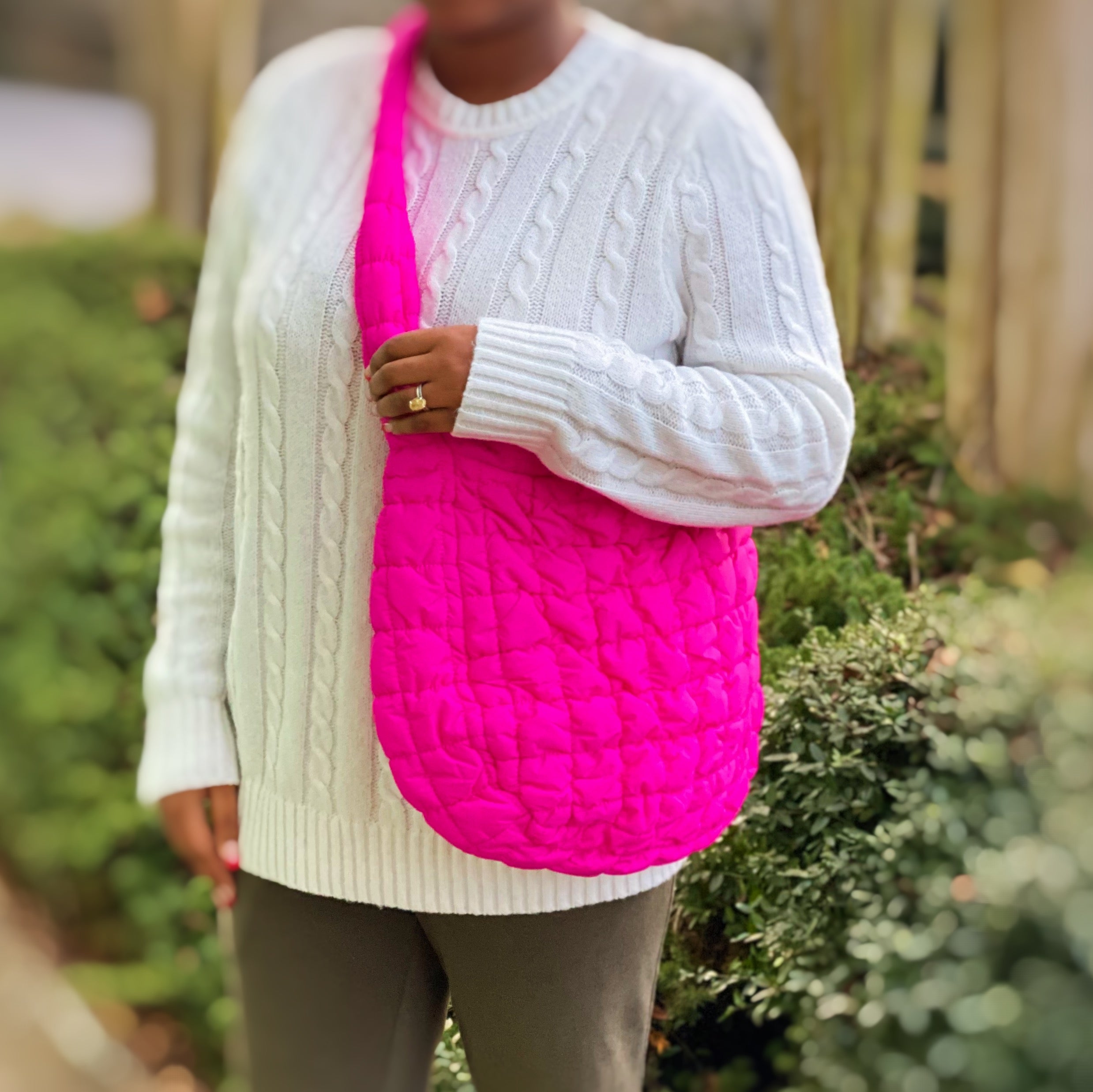 Woman holding a Carry All Quilted Cross Body Bag while wearing a cozy white sweater.