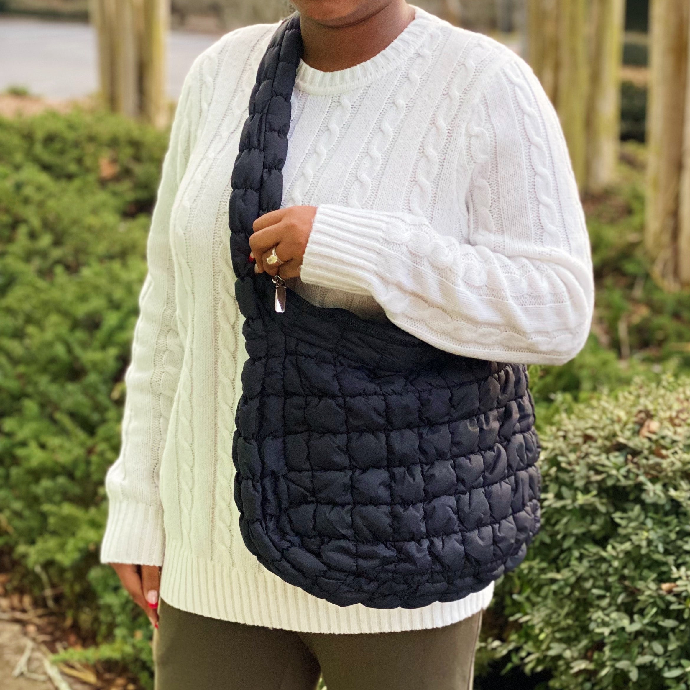 Woman holding a Carry All Quilted Cross Body Bag while wearing a cozy white sweater.