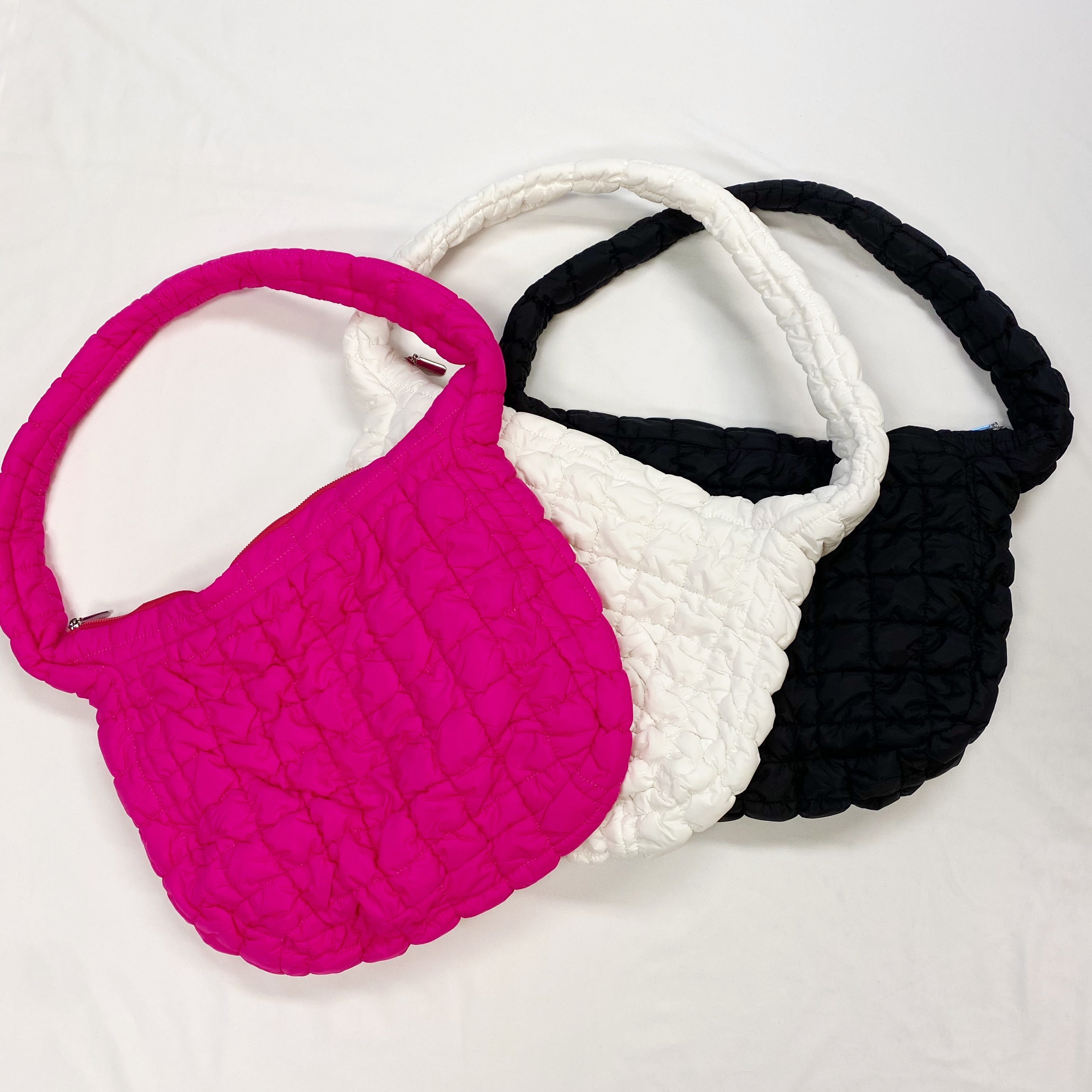Woman holding a Carry All Quilted Cross Body Bag while wearing a cozy white sweater.